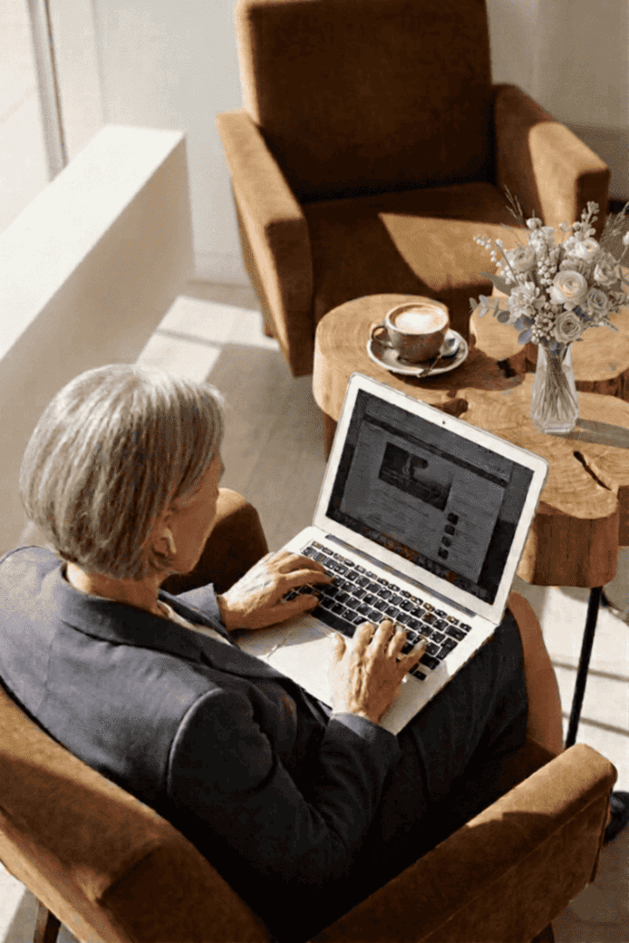 Femme assise dans un fauteuil travaillant sur son ordinateur